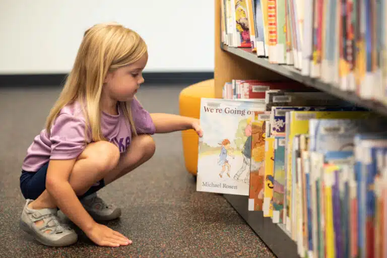 A girl crouches to get a book at Daviess County Public Library.